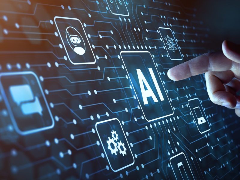 Image of a hand pointing to a dark graphic with icons including one saying AI to illustrate artificial intelligence