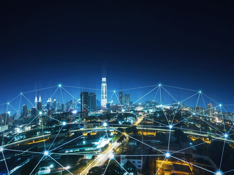 city at night from the air with lines representing communications between buildings