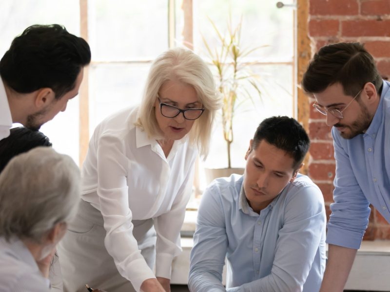 team of men and women looking down at information on a table