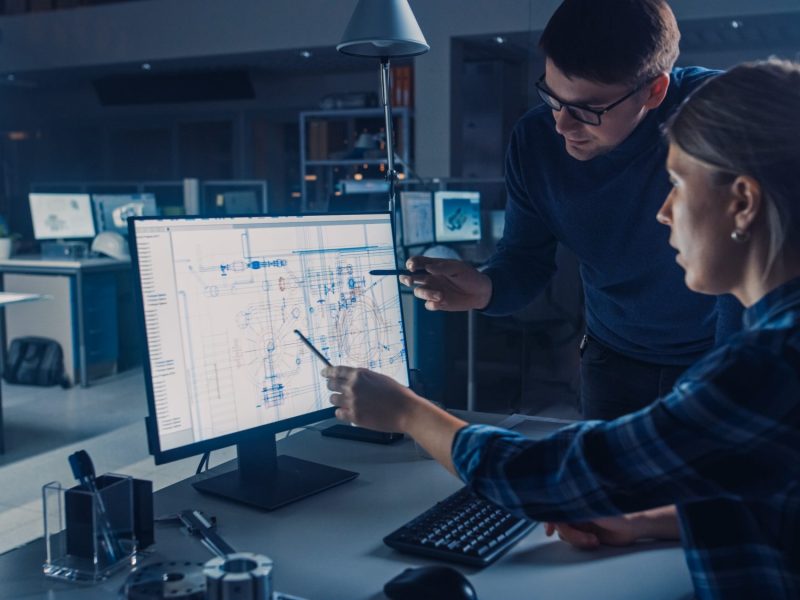 Male and female engineers working on display screen