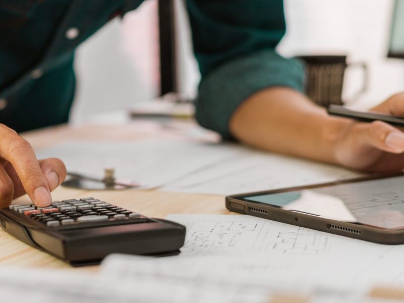 The arms of a person using a calculator and a tablet