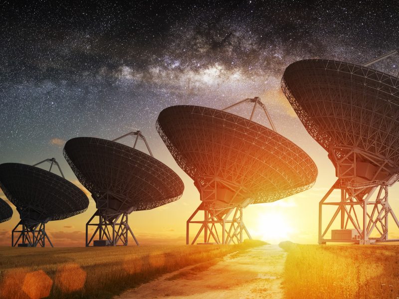 Satellite ground station antennas with orange sun shining through