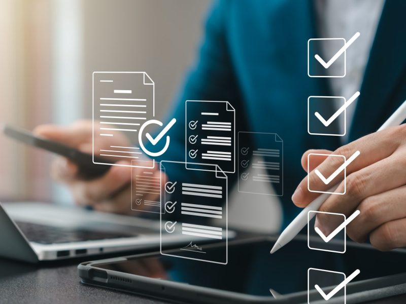 woman's hands holding stylus above a tablet with overlaid graphics of ticks and checklists