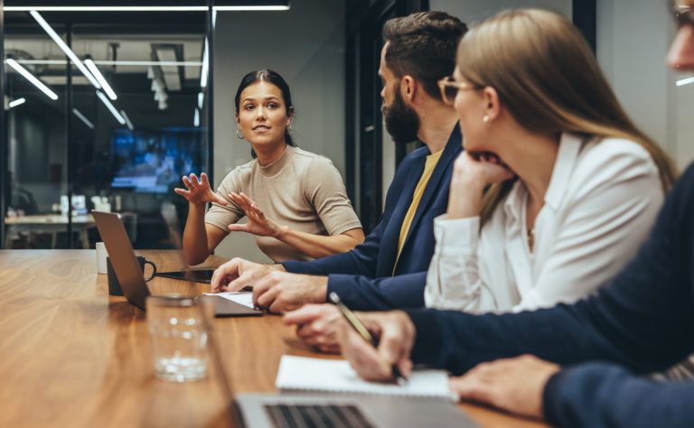 woman talking to team at table with laptops